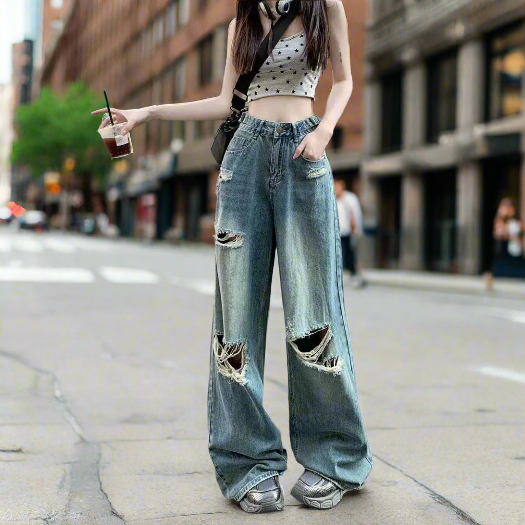 Person wearing ripped jeans and a crop top on a street.