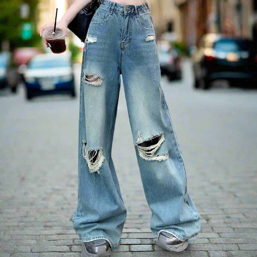 Person wearing ripped blue jeans and a crop top, standing on a street.