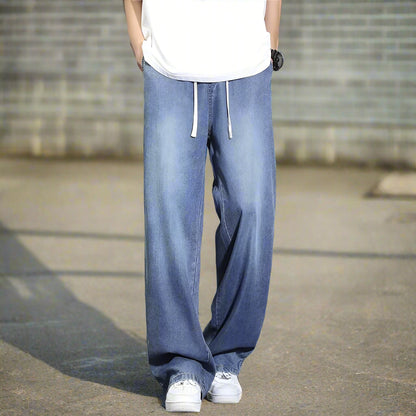 Person wearing light blue jeans and white sneakers on a gray background