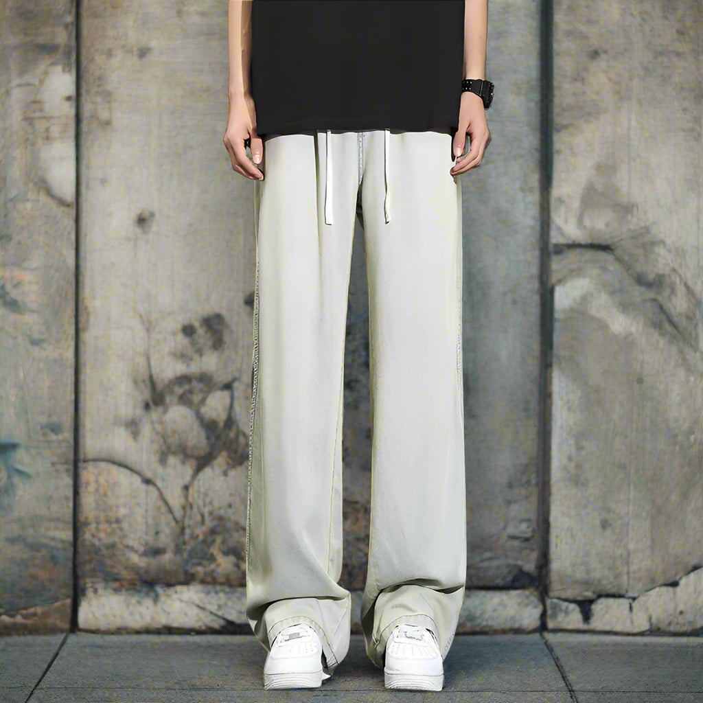 Person wearing light gray wide-leg pants and white sneakers on a old style street,